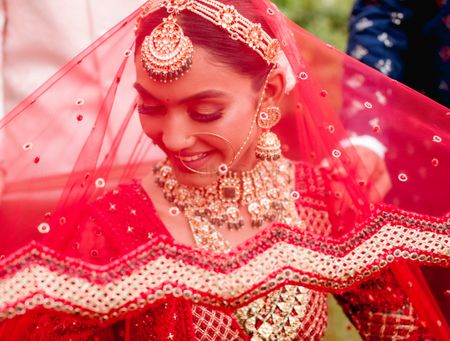 Photo of Stunning bridal portrait with a red sequined overhead dupatta