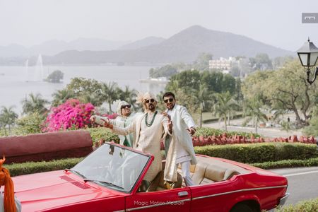 Photo of Groom and his baraat entering in a fun vintage red car