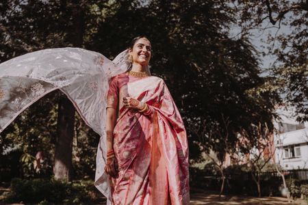 Photo of bride in gold and pink silk saree with flying veil