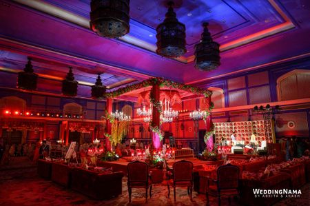 red mandap indoors with chandeliers hanging
