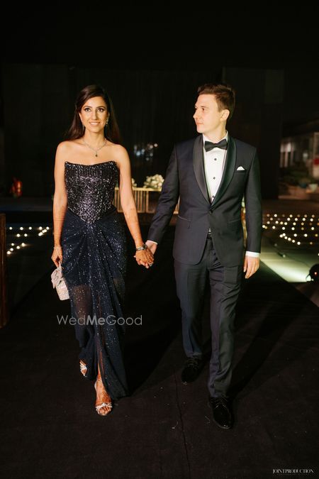Photo of Bride and groom in coordinated black and silver outfits with the bride in a sparkling strapless gown