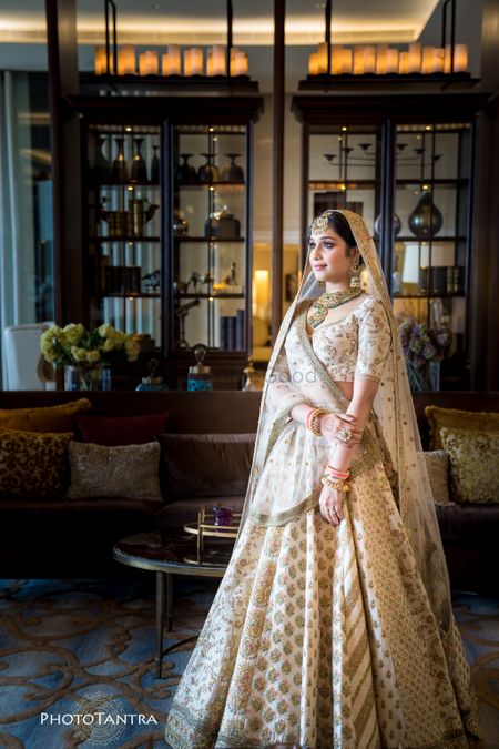 A bride in an ivory and gold lehenga with double dupatta