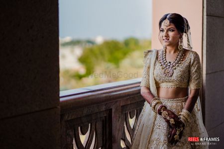 A bride in an ivory and gold lehenga with stunning jewelry on her wedding day