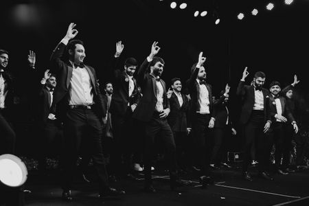 Fun black and white shot of groom and groomsmen dancing in co-ordinated outfits