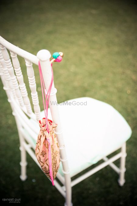 Photo of White wedding chairs with light pink bag