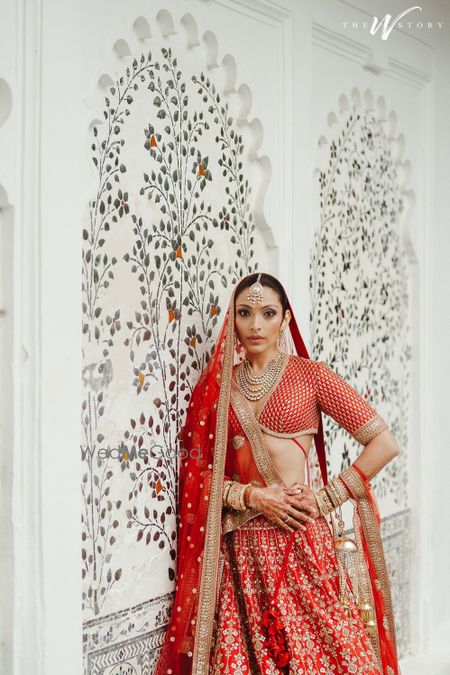 Classic bridal portrait on the wedding day with the bride in a timeless red lehenga with a plunge neck blouse and diamond jewellery