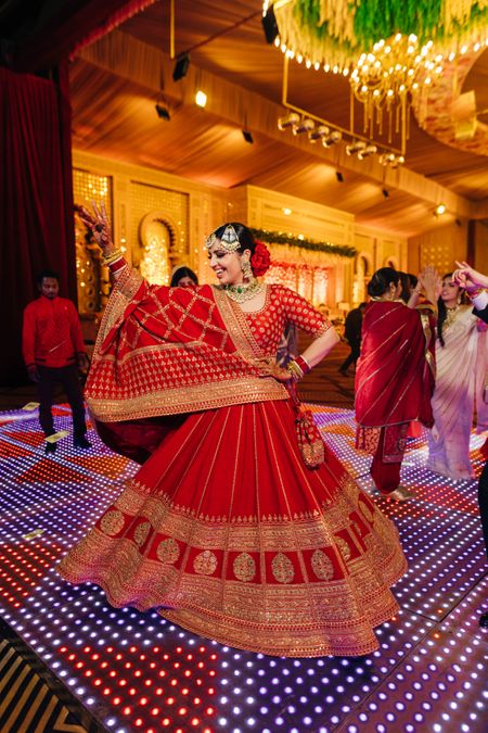 Photo of happy bride twirling in red lehenga
