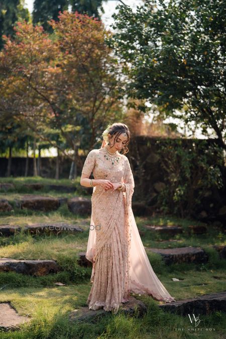 Gorgeous wedding day bridal portrait with the bride in a peach saree and emerald jewels