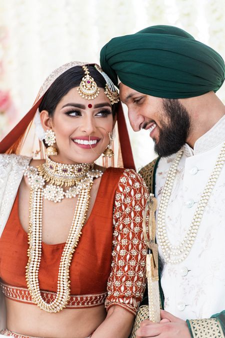 Bridal portrait with layered jewellery and happy groom 