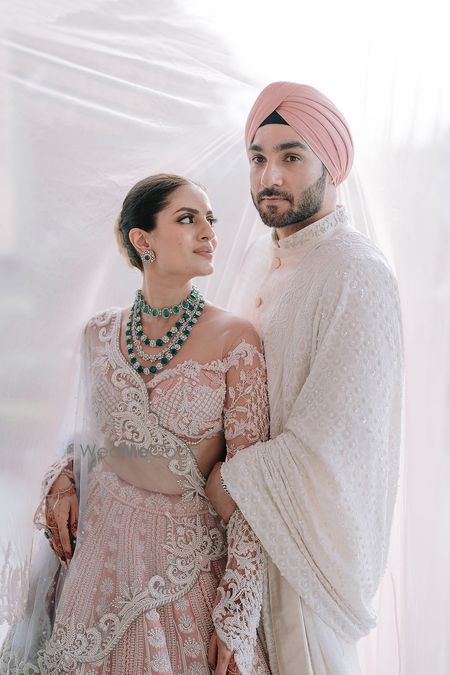 Photo of Stunning couple portrait on wedding day with the bride in a stunning sheer blouse and peach lehenga
