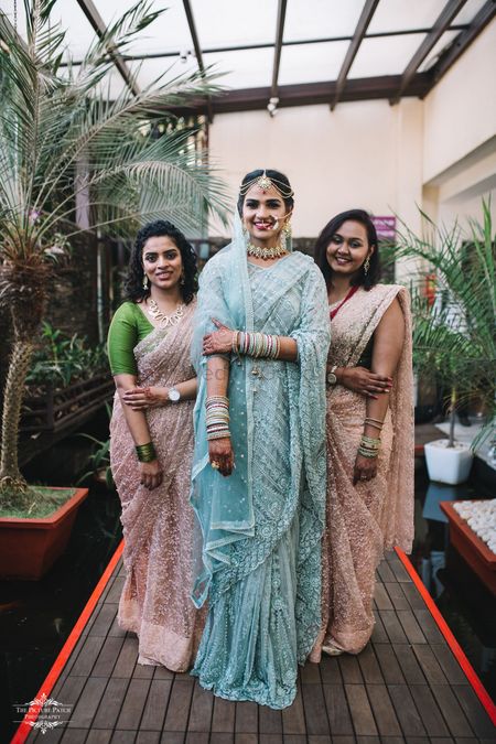 A bride in a tiffany blue saree with bridesmaids in matching peach outfits