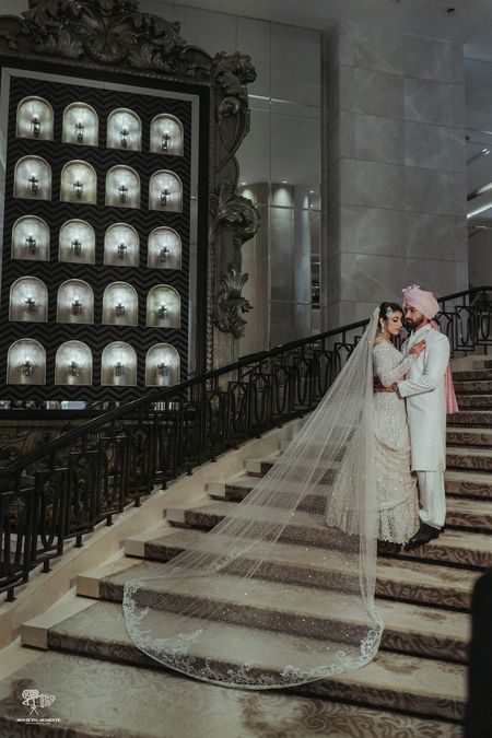 bride and groom portrait on stairs with trail lehenga dupatta