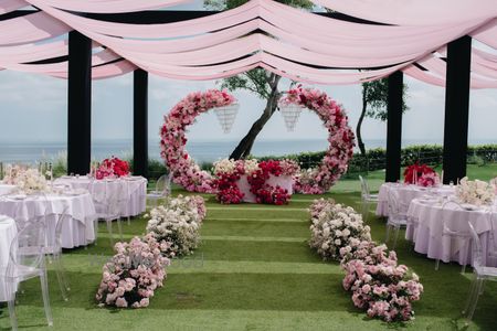 Stunning blush pink floral decor for a stage set up with light pink drapes for an outdoor event 