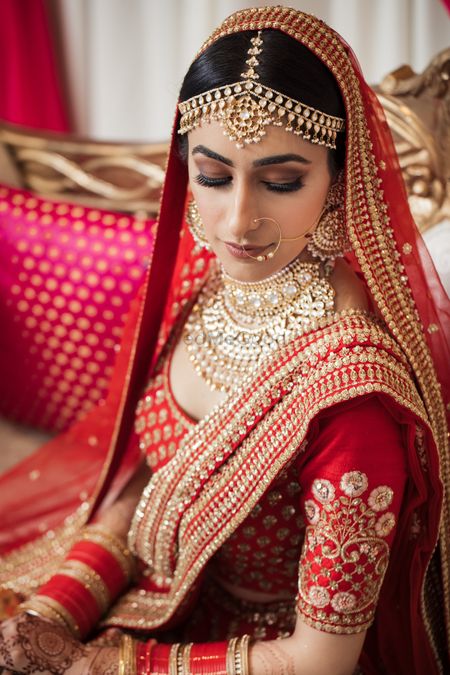 Photo of Close up shot of a bride wearing a red Sabyasachi lehenga on her wedding.