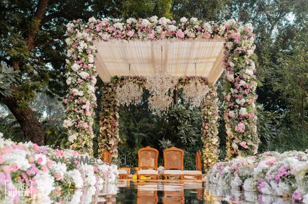 Gorgeous floral mandap with crystal chandeliers for an outdoor wedding