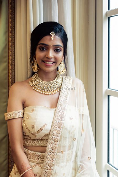 A bride in a beige and gold offshoulder outfit with a gold choker and messy plait for her engagement