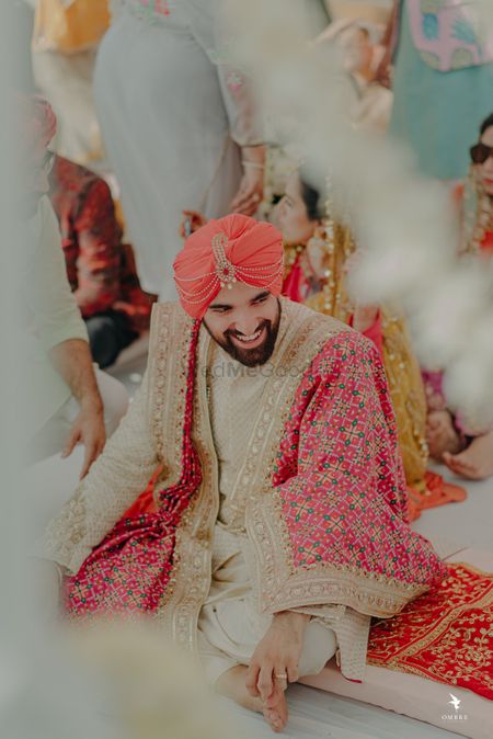 The groom in a beige sherwani, and a bright pink dupatta