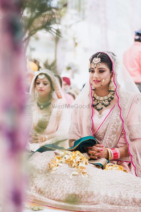 A Sikh bride in soft pink lehenga fir her anand karaj