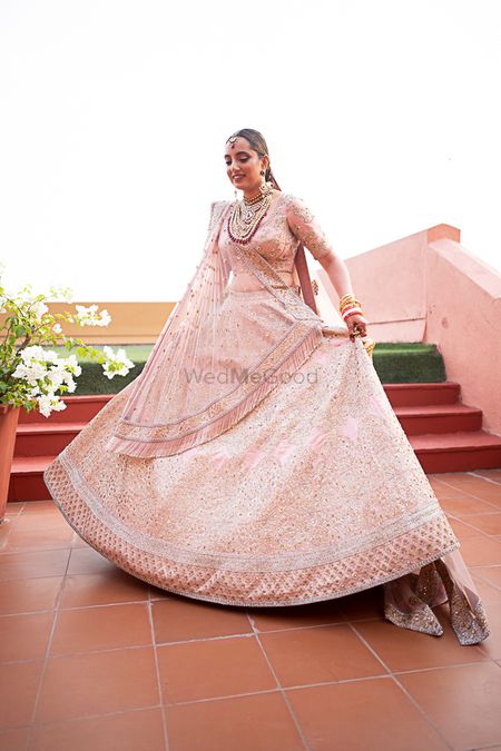 Bride dressed in pink lehenga posing on her wedding day.