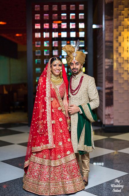 Red bridal lehenga with the groom in emerald