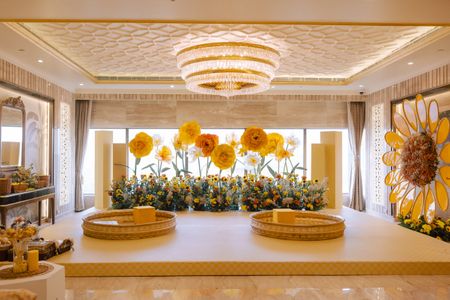 Oversized yellow floral decor backdrop for a haldi ceremony with gold urlis