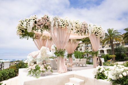 Photo of modern mandap decor idea with peach drapes and lots of florals