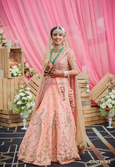 Photo of Sikh bride with peach lehenga and green jewellery