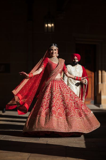 Photo of Twirling shot of a bride dressed in a red lehenga.