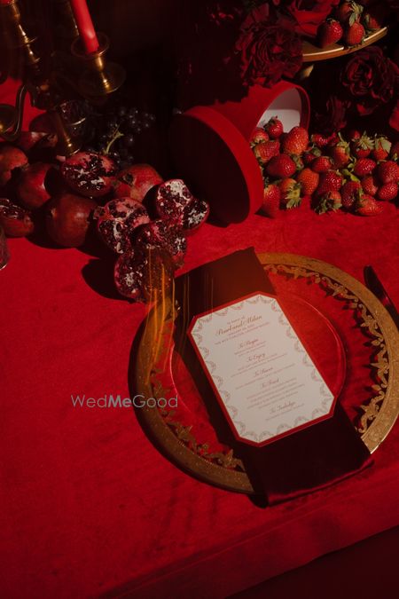 Photo of Unique table setting in all red with fruits as decor and a personalised menu for the reception event