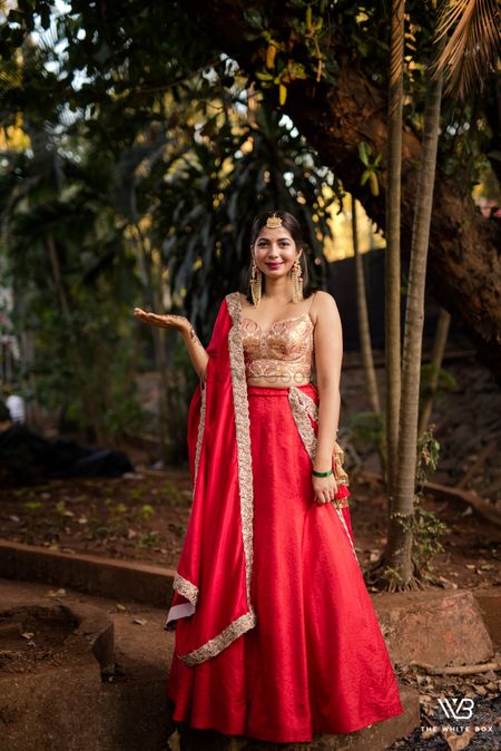 A bride to be in a red and gold lehenga for her mehndi