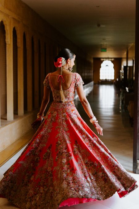 Photo of bride twirling in coral lehenga