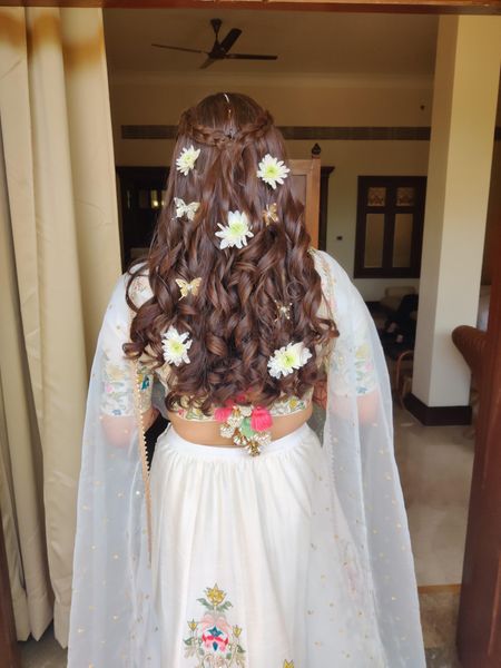 Half tied hair with a crown braid and floral adornments.