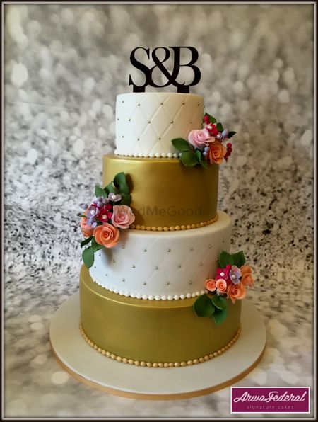 Photo of Gold and white 4 tier wedding cake with monogram topper