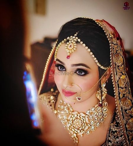 A bride with peach and gold jewelry poses for the camera. 