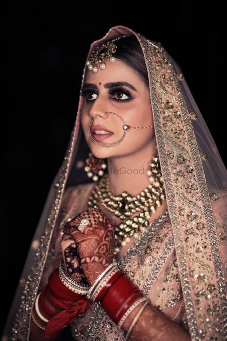 Candid shot of a bride dressed in pastel pink lehenga.