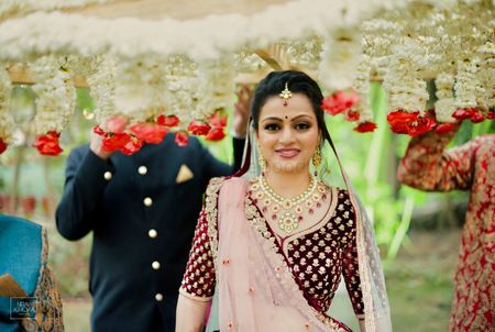 Bride in maroon lehenga under phoolon ki chadar 