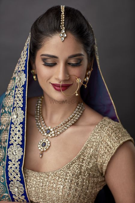 Photo of Emerald and diamond necklace with blue and gold lehenga