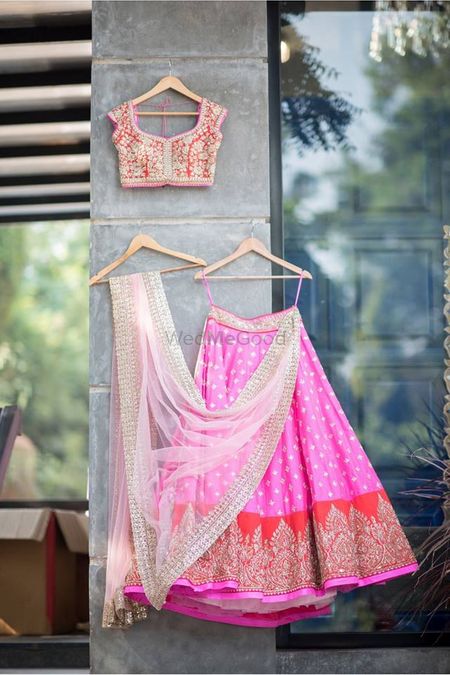 Light bridal lehenga on hanger in pink and red 