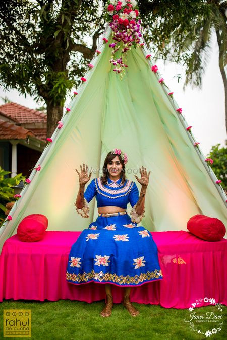 A bride in blue posing in front of a teepee tent on her mehndi 