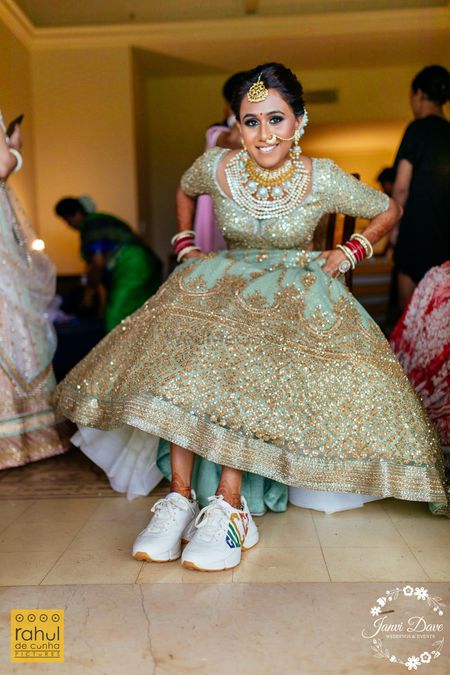 A bride in an embellished sea green lehenga with sneakers