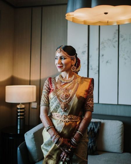 South Indian bride wearing a gold saree with an embellished blouse & temple jewellery.