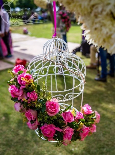 Photo of White birdcage with pink and green floral arrangement