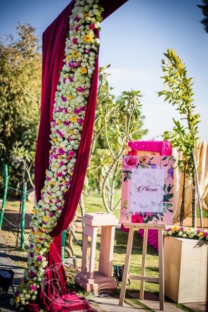 Photo of Floral arrangement at mandap entrance with pheras board