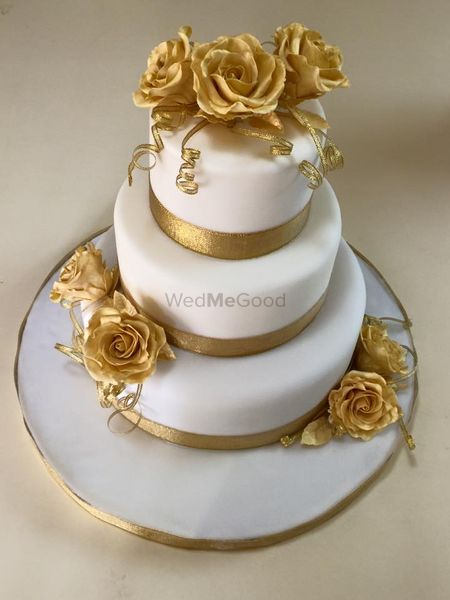 Photo of 3 tier white wedding cake with gold flowers