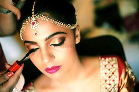 Bridal makeup with gold eyes and bright pink lips and mascara