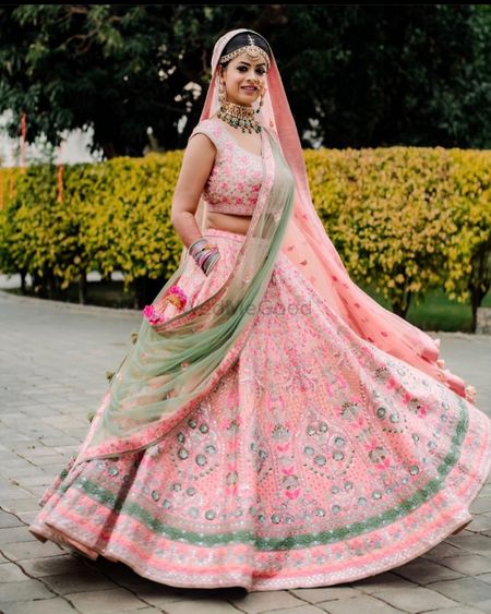 Bride twirling around in a baby pink lehenga.