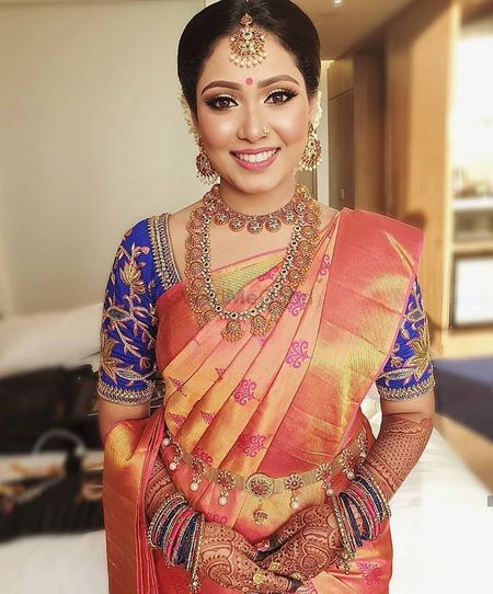 Southi Indian bride dressed in a coral saree with a navy blue blouse.