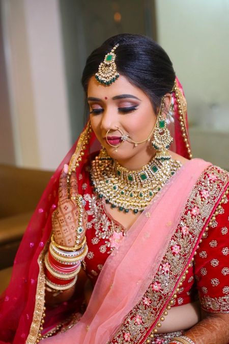 Photo of A bride in red and pink outfit with exquisite bridal jewelry