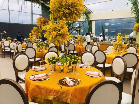 Table settings done with yellow table spreads and wooden chairs.