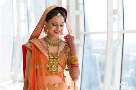 bride wearing coral and red lehenga 